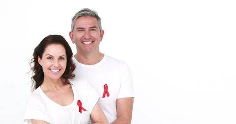 Smiling couple promoting hiv awareness with red ribbons