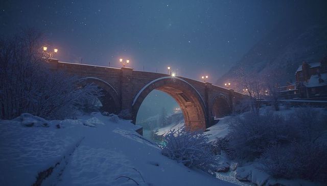 Illuminated stone bridge in winter night landscape with snow