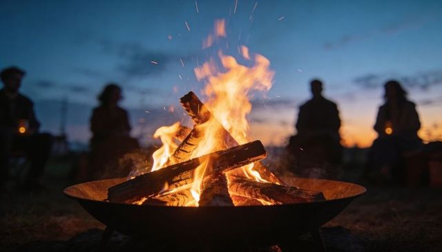 Cozy campfire gathering at twilight with warm flames, glowing embers and silhouetted friends