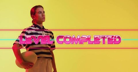 Posing Female Athlete Holding Ball with Neon LEVEL COMPLETED Text on Vibrant Yellow Background