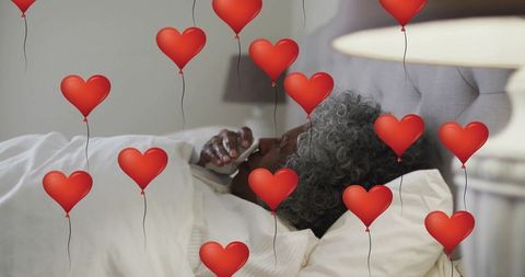 Senior woman relaxing past heart balloons in cozy bedroom