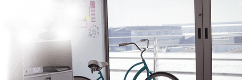 Bicycle resting by glass window in creative modern office