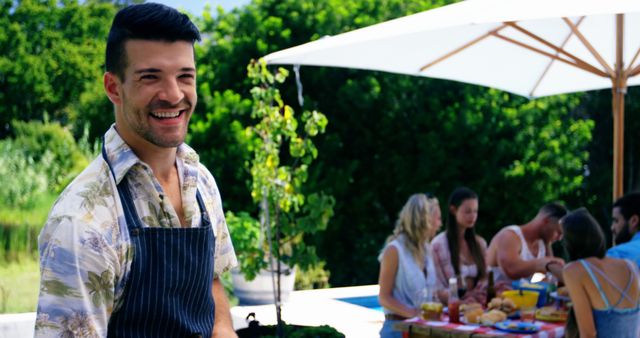 Smiling man wearing apron at outdoor summer picnic with friends - Download Free Stock Images Pikwizard.com