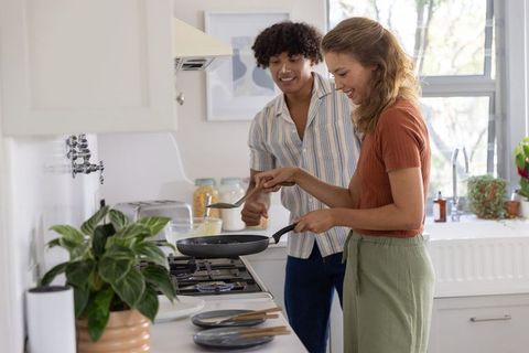 Young couple cooking together in bright modern kitchen smiling during breakfast moment