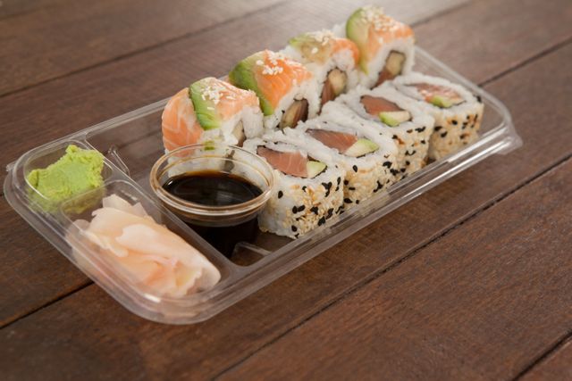 Set of assorted sushi served in a plastic box on wooden table