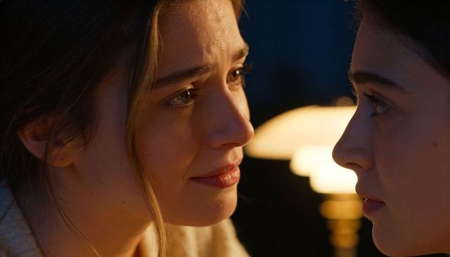 Two women gazing closely sharing tender moment by warm lamp glow intimate portrait