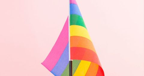 Close-up of Rainbow Flag Against Pink Background Symbolizing Pride
