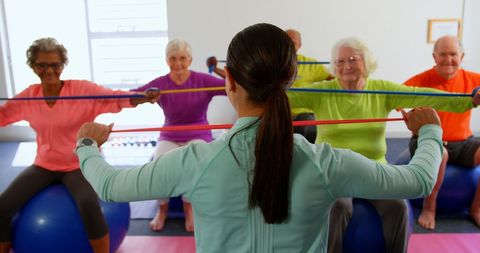 Senior Group Exercising with Resistance Bands in Fitness Class