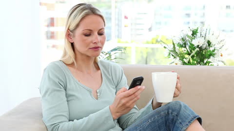 Blonde Woman Relaxing with Coffee and Smartphone at Home
