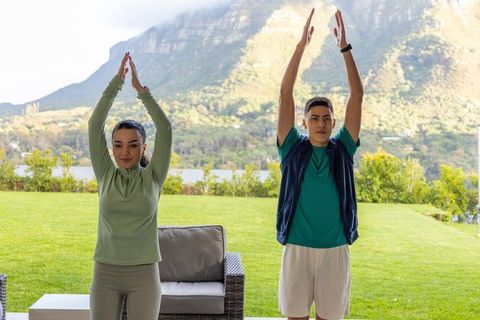 Couple stretching on covered patio overlooking lake and mountains for outdoor fitness