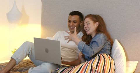 Couple Celebrating Engagement on Laptop in Cozy Bedroom Setting