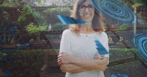Smiling mature woman standing in backyard wearing glasses and pendant with futuristic hud