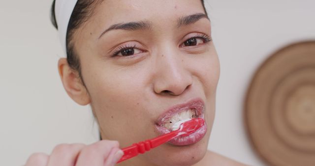 Portrait of biracial woman brushing teeth in bathroom. Beauty, health and female spa home concept.