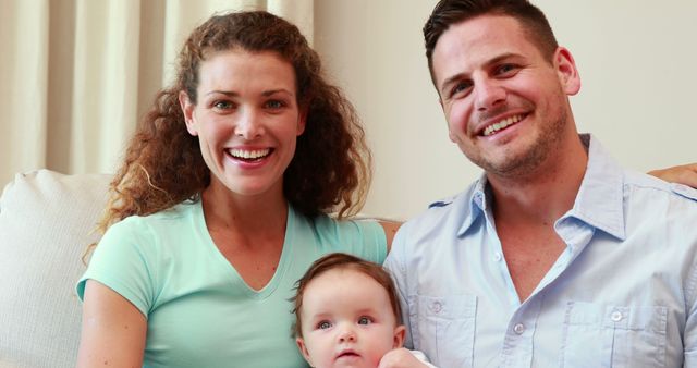 Smiling Parents with Baby on Couch in Cozy Living Room - Download Free Stock Images Pikwizard.com