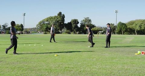 Coach leading trainees performing shuttle run drill on outdoor grass field