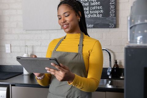 African American Barista Checking Tablet While Managing Cafe Orders Behind Counter