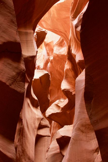 This stock photo captures an intricate view of sandstone formations in a slot canyon with sunlight streaming through the narrow openings. The swirling patterns and earthy tones present a breathtaking natural wonder. The image is ideal for use in travel brochures, geological study publications, tourism advertisements, nature photography exhibits, and digital backgrounds focused on natural beauty and unique landscapes.