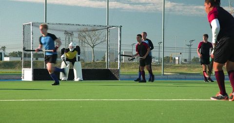 Field hockey players defending goal on outdoor field during match