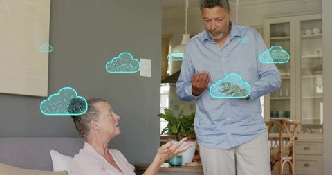 Senior couple discussing cloud technology at home with floating turquoise cloud icons