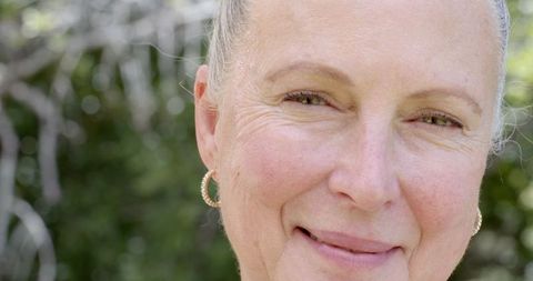 Smiling Senior Woman in Garden with Gold Hoop Earrings