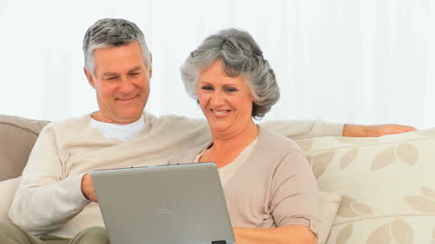 Senior Couple Enjoying Leisure Time on Laptop at Home