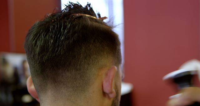 Close-up of a haircut in progress at a barbershop. Precision and style focus as a barber shapes a client's hair.