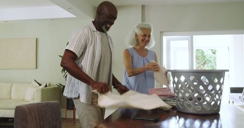Smiling Couple Folding Clean Laundry in Bright Cozy Living Room