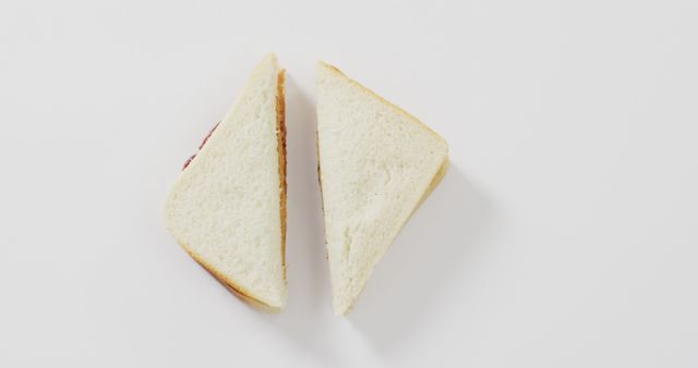 This stock photo features a simple triangle sandwich made with white bread on a white background. Ideal for use in food-related websites, meal prep blogs, minimalist design projects, or advertisements for breakfast items and snacks.