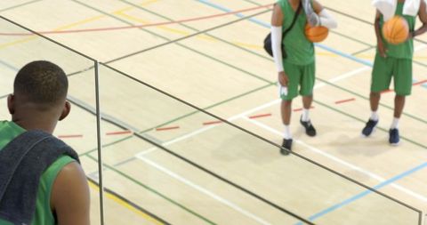 African american basketball player greeting teammates from gym balcony, team camaraderie