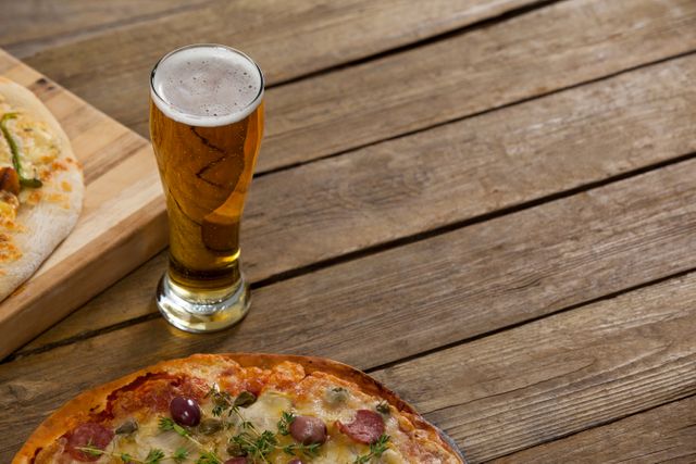 Delicious pizza served on wooden board with a glass of beer on wooden plank