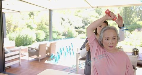 Senior woman doing guided arm rehabilitation with caregiver using AR fitness overlay on patio