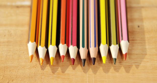 A set of colorful pencils is arranged in a row on a wooden surface, with copy space. These pencils are essential tools for artists, students, and anyone engaged in writing or drawing activities.