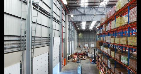 Busy Warehouse Interior With High Pallet Racking, Forklifts and Staff Loading Deliveries