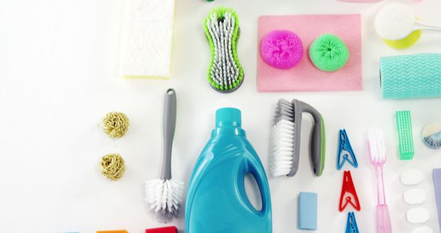 Image showcases a variety of cleaning products and tools neatly arranged on a white background. Includes items such as a blue bottle of detergent, various sponges, scrubbing brushes, scouring pads, sanitary pads, and cloths. Ideal for use in articles about household cleaning routines, product comparisons, sanitation, or advertisements for cleaning supplies.