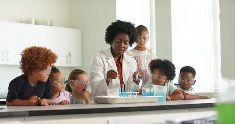 Black teacher guiding diverse elementary students during hands-on science experiment
