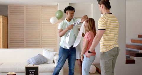 Friends celebrating new job with happy balloons in living room