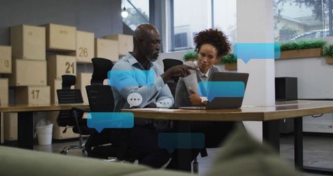 Mentor guiding colleague over laptop in modern coworking space for teamwork and coaching