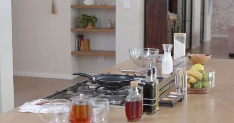 Contemporary kitchen island featuring gas cooktop, frying pan, mixing bowls and fruit