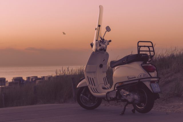 Vintage Vespa scooter parked near a sandy beach at sunset with a calm sea in the background. Ideal for illustrations about travel, summer vacations, leisurely beach rides, lifestyle, and seaside adventures. Suitable for travel agencies, automotive, and tourism campaigns.