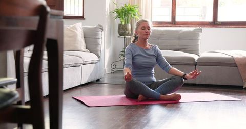 Senior Woman Meditating at Home on Pink Yoga Mat