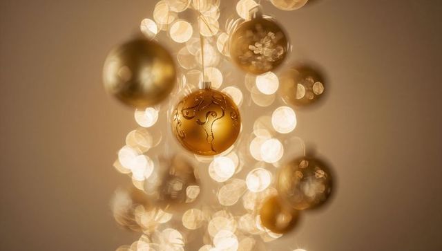 Ornate Gold Holiday Bauble Hanging with Etched Swirls and Soft Warm Bokeh Glow