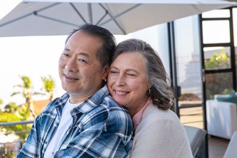 Happy Diverse Couple Embracing at Outdoor Patio Overlooking Lush Garden