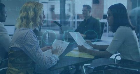 Female Coworkers Discussing Reports with Digital Overlay in Modern Office