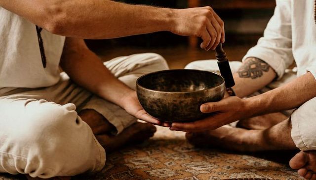 Partner sound healing using singing bowl and mallet during intimate meditation ritual