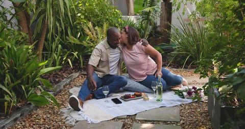 Romantic Garden Picnic with Diverse Couple Sharing Laughter and Wine