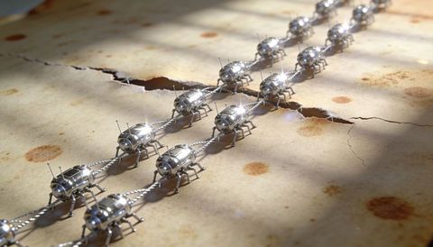 Parallel chrome beetle chain reflecting light on cracked paper with diagonal shadows