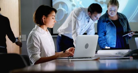 Focused businesswoman working on laptop in collaborative office