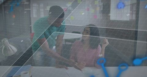 Young professionals collaborating over documents with digital data overlay in office