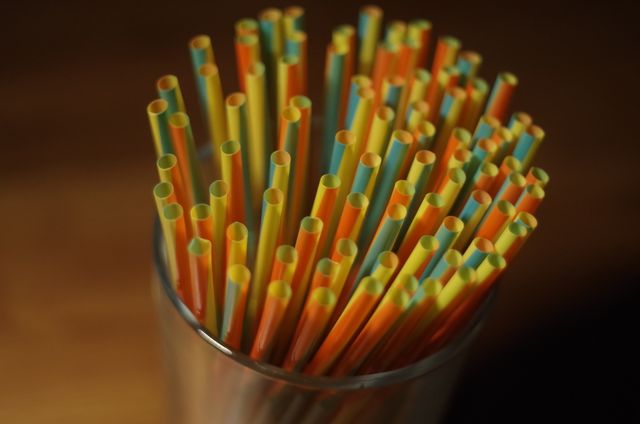 Colorful drinking straws arranged in a glass cup seen from above. Ideal for illustrating themes related to beverages, party supplies, and eco-friendliness. Can be used in advertisements, invitations, or articles focused on kitchen accessories, environmentally friendly alternatives to plastic, or vibrant party essentials.