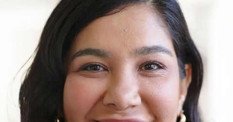 Confident woman smiling and making eye contact wearing gold hoop earrings closeup portrait